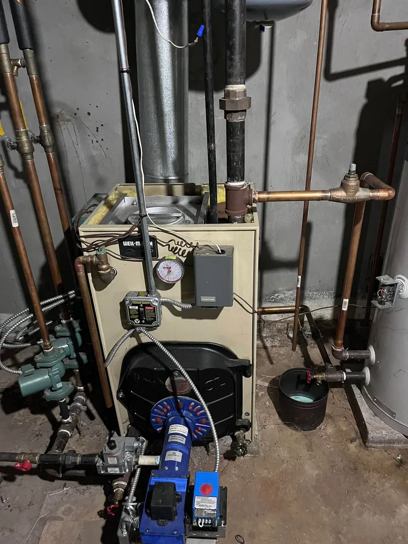 A boiler with its near-boiler copper piping, circulator and controls installed in a basement.