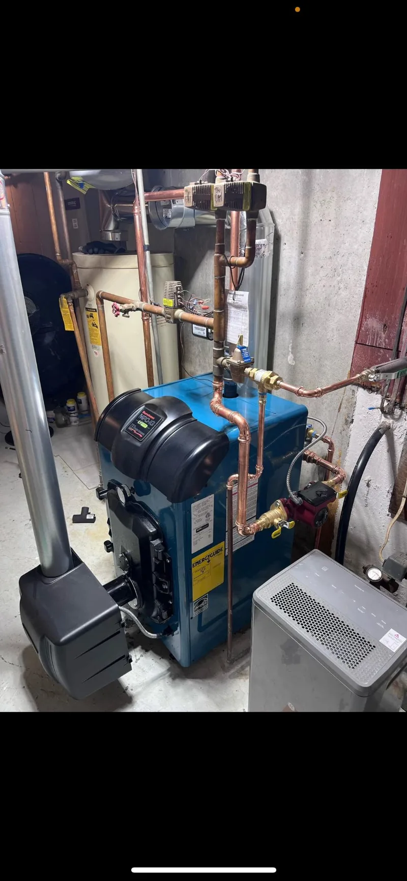 Basement heating equipment with a circulator pump and copper supply and return lines.