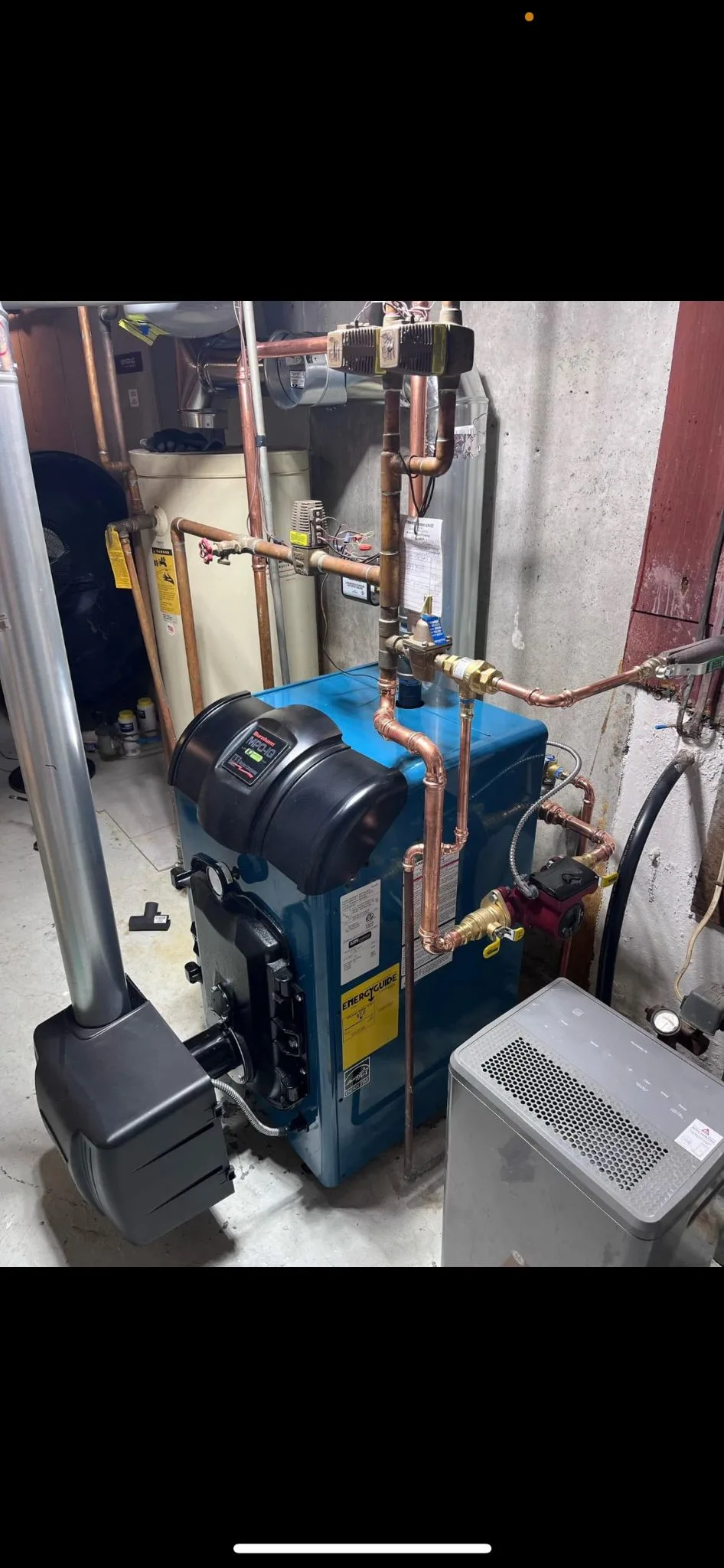 Basement heating equipment with a circulator pump and copper supply and return lines.