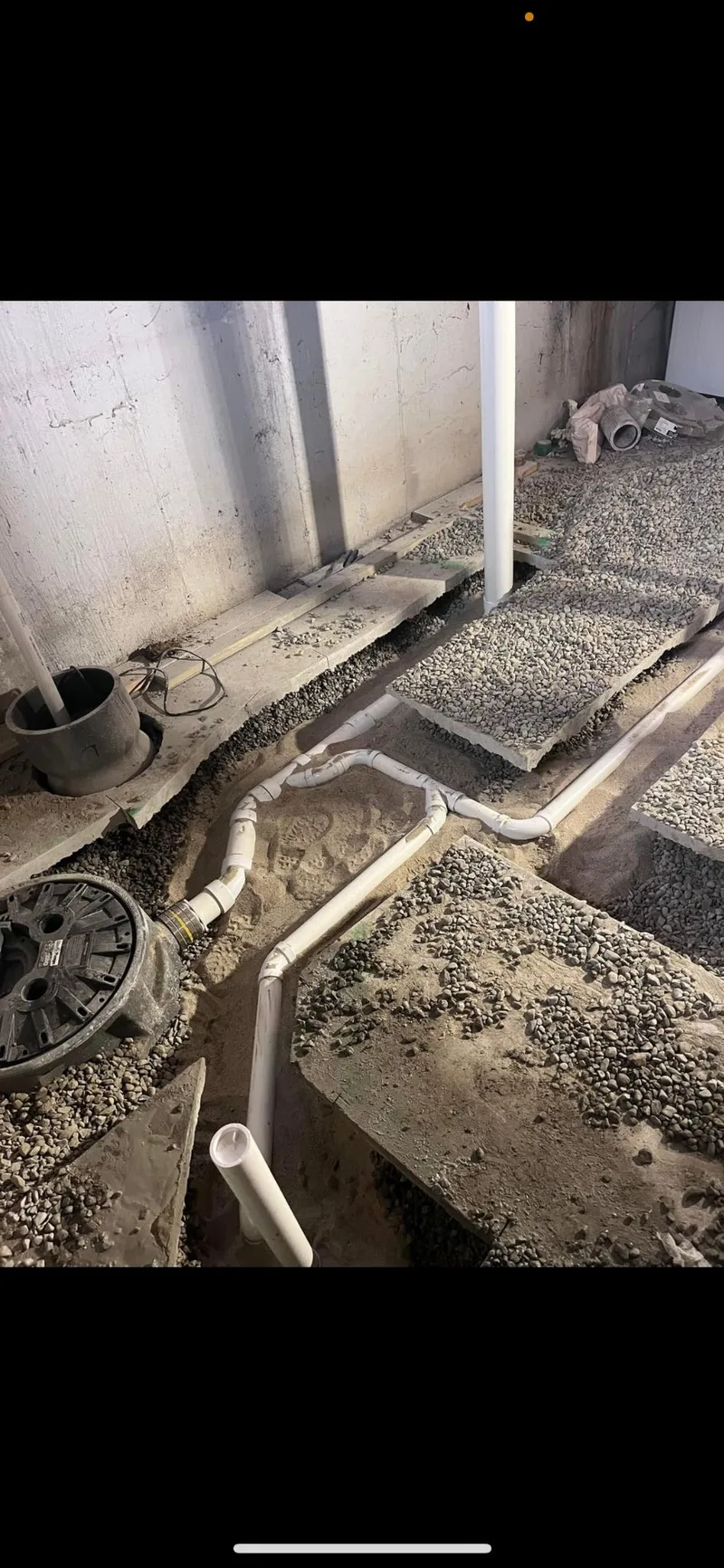 A drain line set into a gravel bed before a slab is poured over it.