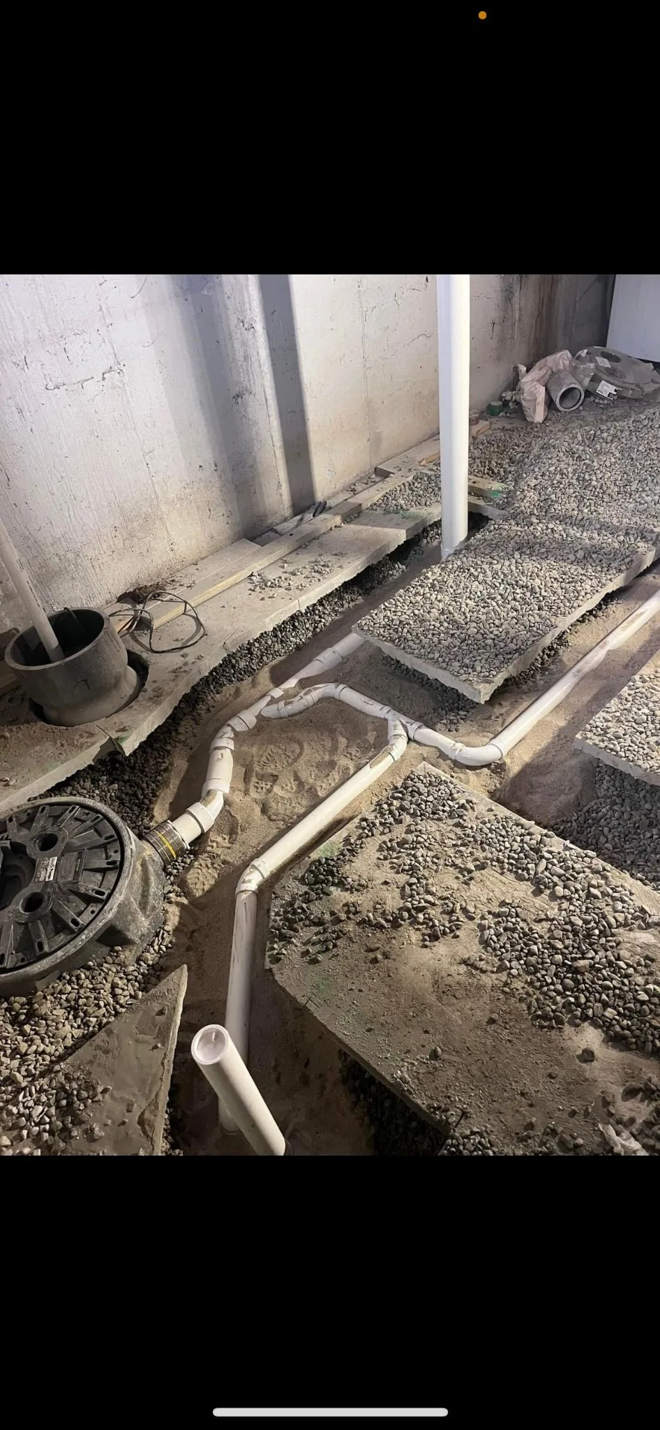 A drain line set into a gravel bed before a slab is poured over it.