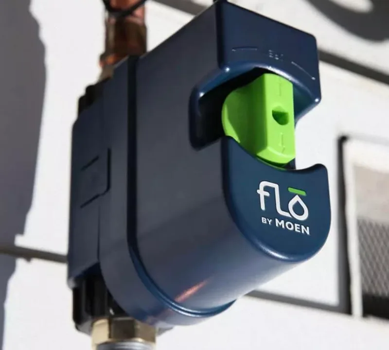 A FLO by Moen automatic shut-off device fitted to the water main on an exterior wall.