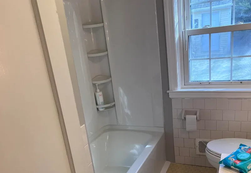 A newly installed bathtub and surround in a tiled bathroom, finished and ready for use.