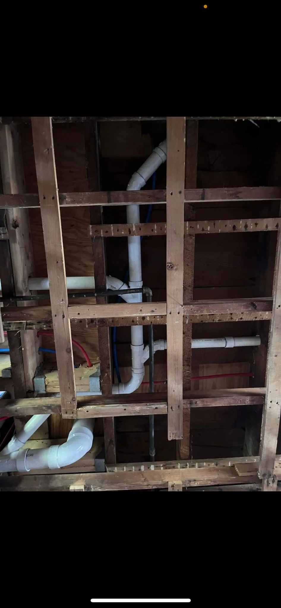 Supply and waste pipework roughed in between open studs before the wall is closed.