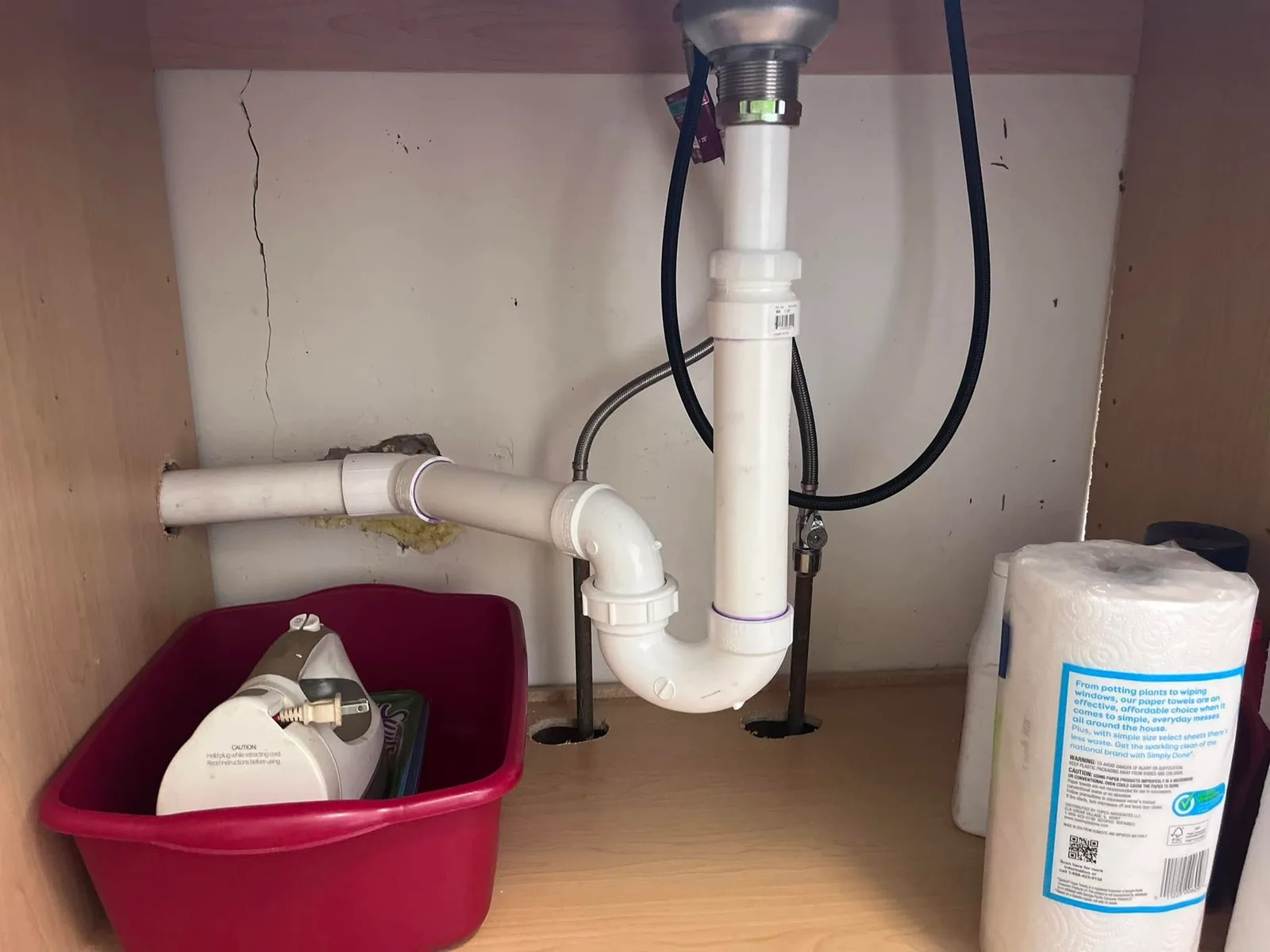 The waste piping and trap arrangement under a kitchen sink, seen from inside the cabinet.