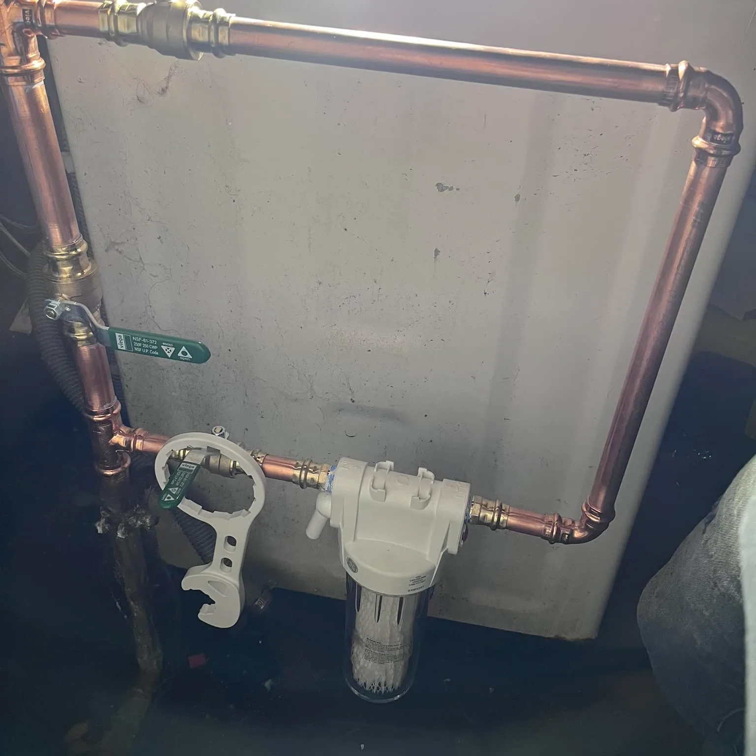 A whole-house water filter housing plumbed into a copper main with isolation valves either side.